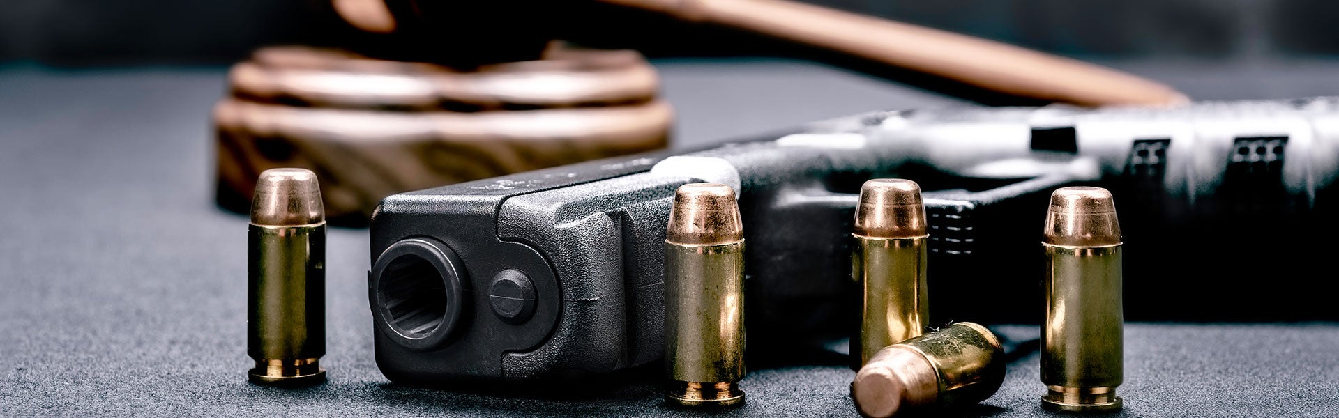 A handgun, bullets, and a judge's gavel on a table emphasizing gun control issues.