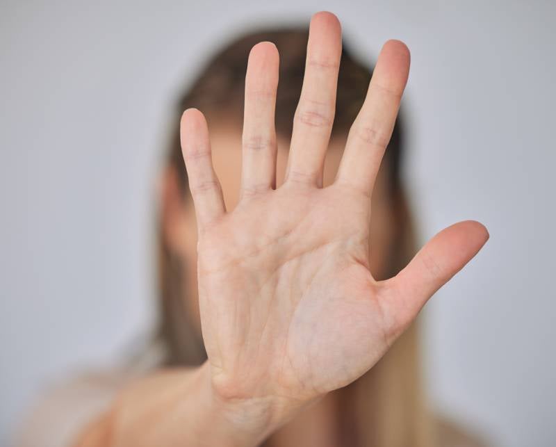 A person's open palm held up to the camera, obscuring their face, indicating stop or no.