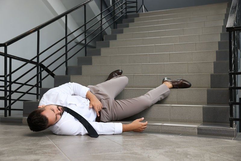 A person lying on the ground in front of stairs